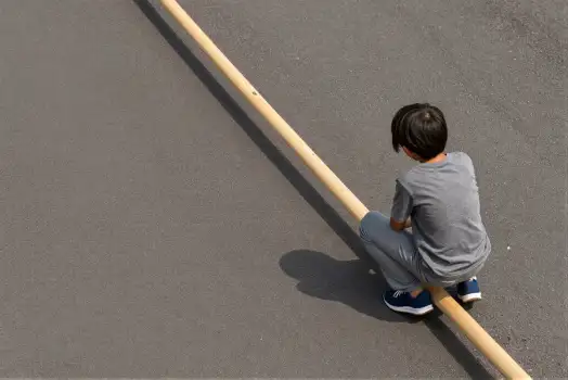Young Boy Holding Wooden Stick in Parking Lot