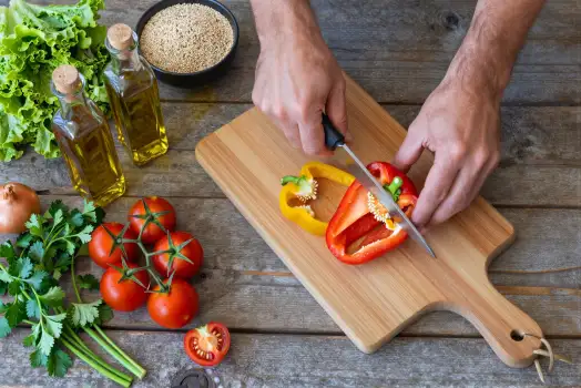 Hands Cutting Bell Pepper on Wooden Board preparing