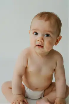 Baby Sitting Curiously on Floor diaper white background